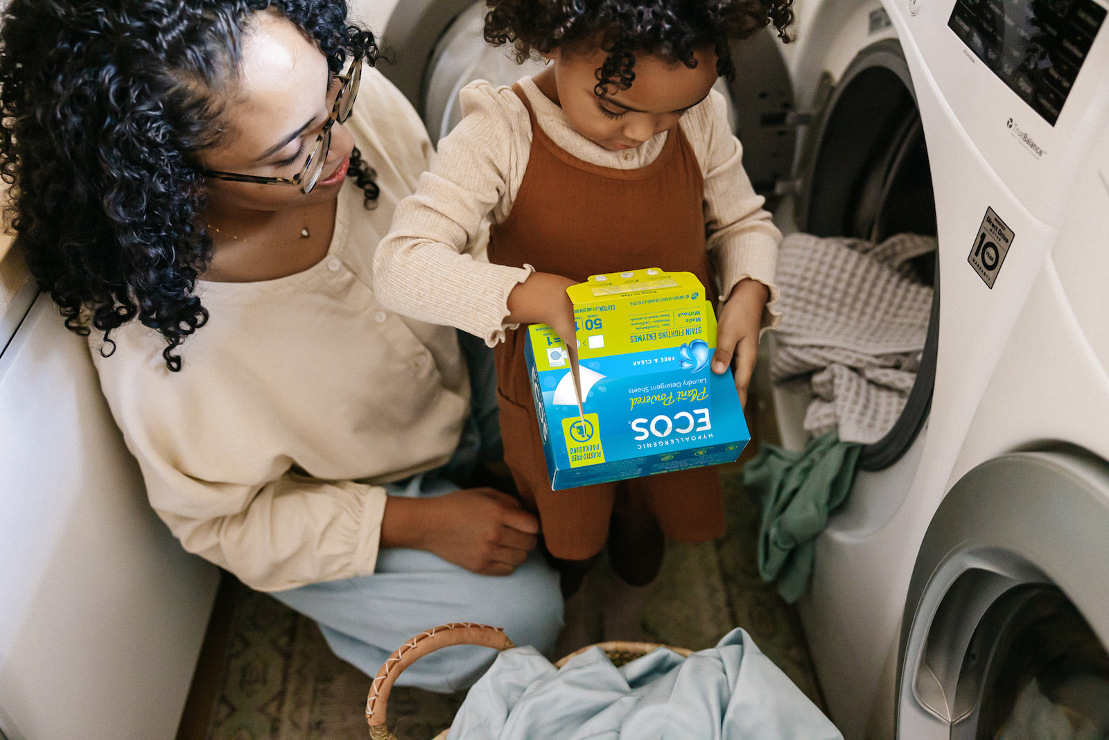 Mother and Daughter Using Laundry Sheet For Load of Laundry